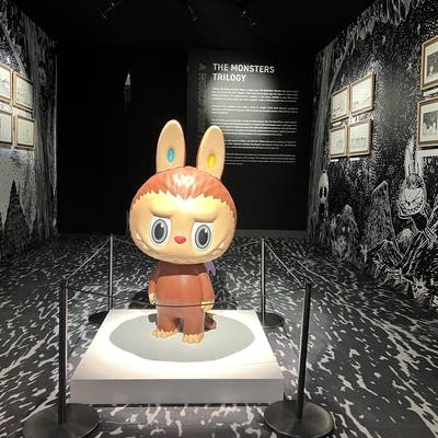 A large Labubu on display in a dark museum room