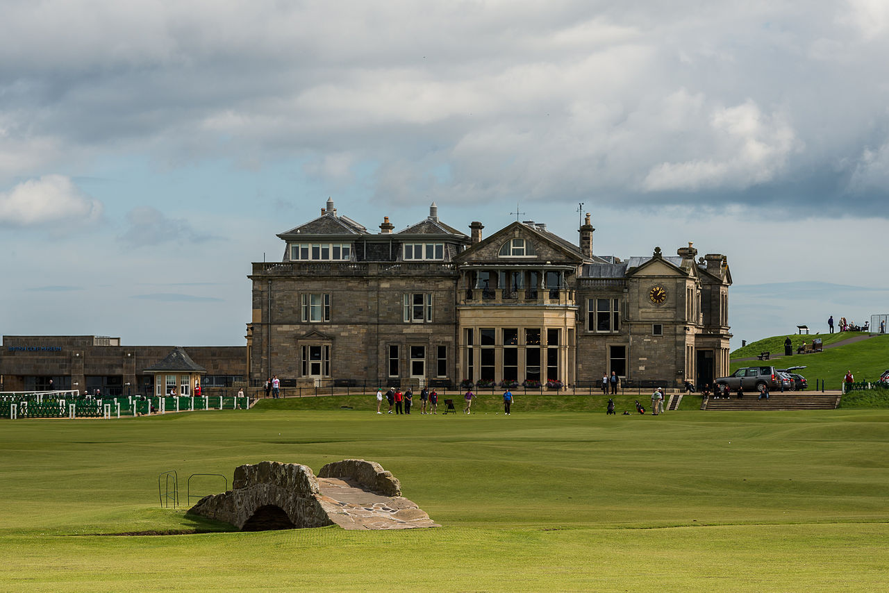 The Royal and Ancient clubhouse behind the 18th green of the Old Course at St Andrews, with the stone Swilcan Bridge in the foreground