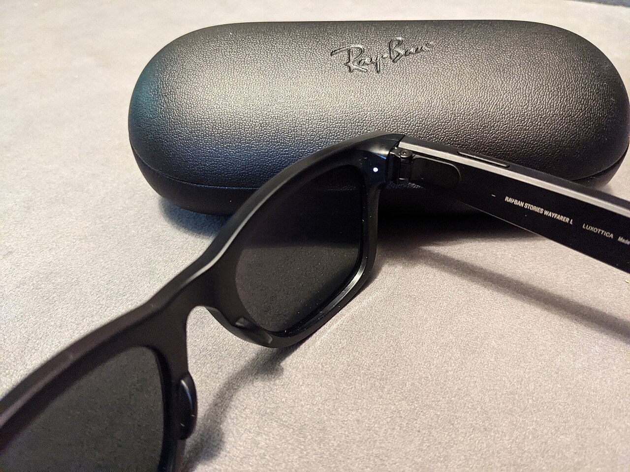 Meta Ray-Ban Stories smart glasses beside their charging case, showing the small capture-indicator LED on the frame