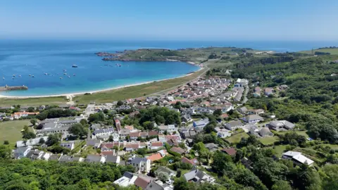 BBC A picture taken from above looking at a number of properties in Alderney. There is a number of homes and trees.