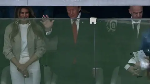 AFP via Getty Images Donald and Melania Trump watching from behind a glass screen