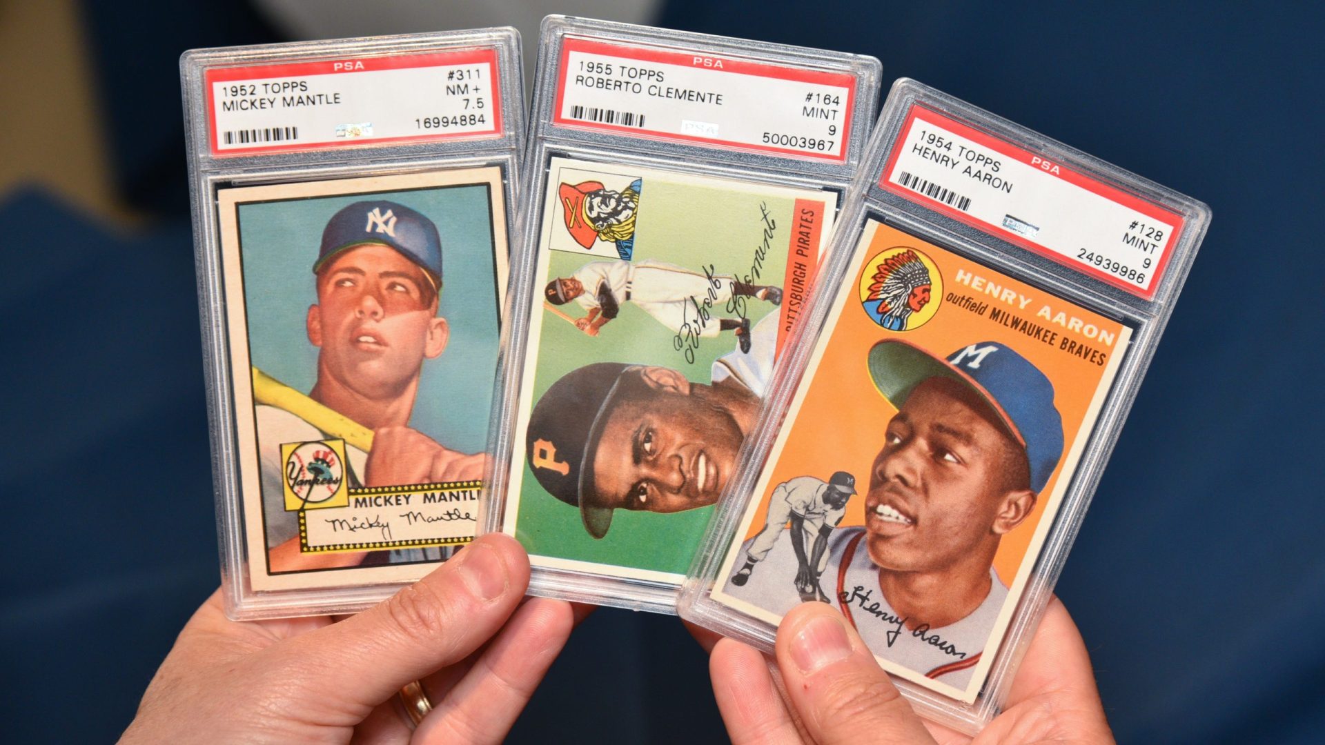Discover person holds vintage mint condition baseball cards featuring Mickey Mantle, Roberto Clemente and Henry Aaron -- license ID 5967104h