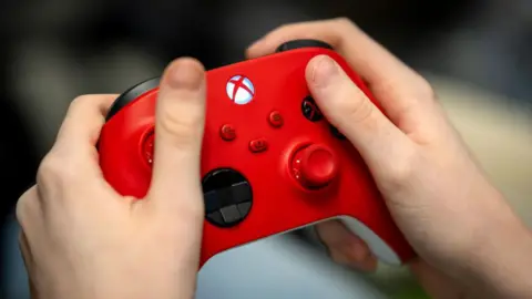 Getty Images Hands holding a red Xbox controller