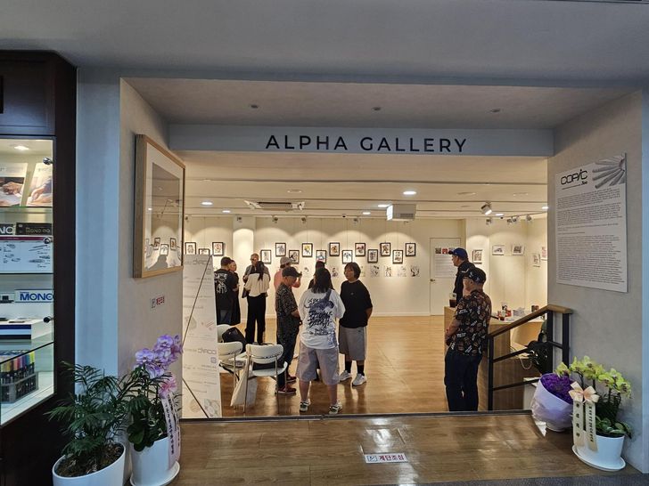 People view art on display at Alpha Stationery in central Seoul's Namdaemun Market, July 11. Comic book legend Bob Layton is third from left, and Dice & Comics Cafe owner Joey Croner is second from right. Courtesy of Agrim Bhalla