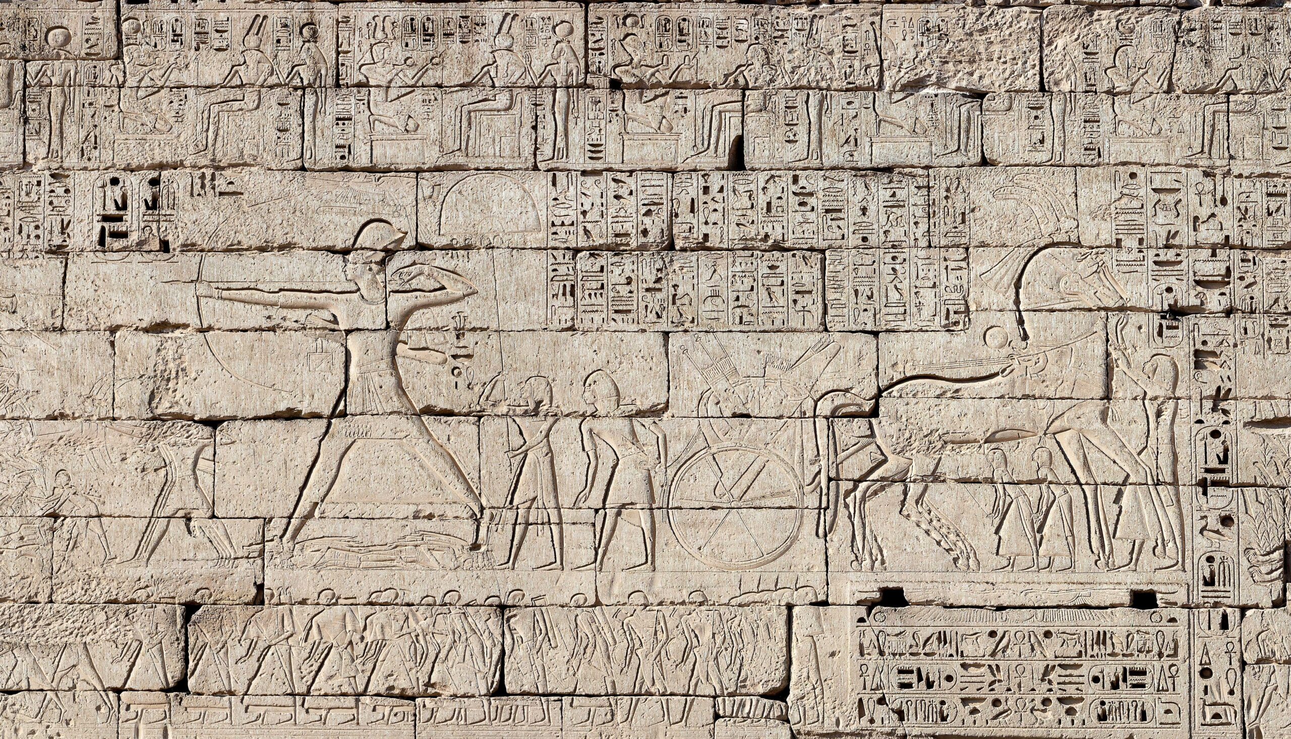 Ancient stone relief showing figures and hieroglyphics, depicting a historical scene with human and animal figures
