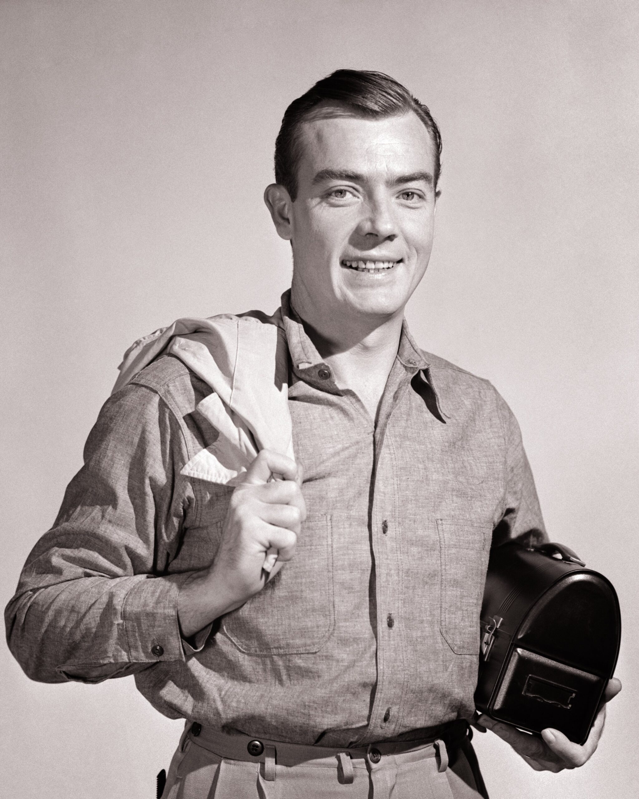 Person in vintage attire holding a small camera, smiling at the camera