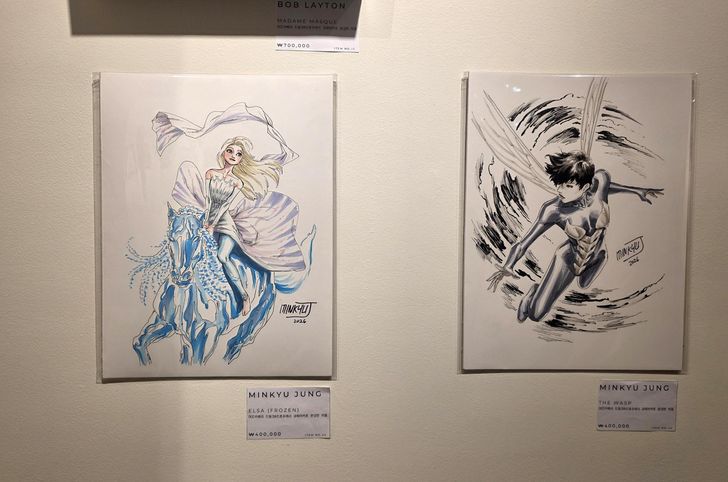 Jung Min-kyu's illustrations of Disney character Elsa, left, and Marvel Comics superhero The Wasp, are on sale for 400,000 won each at Alpha Gallery in central Seoul's Namdaemun Market, July 20. The exhibition continues until Aug. 1. Korea Times photo by Jon Dunbar