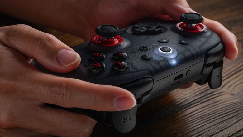 Person using 8BitDo Ultimate 2C translucent black controller