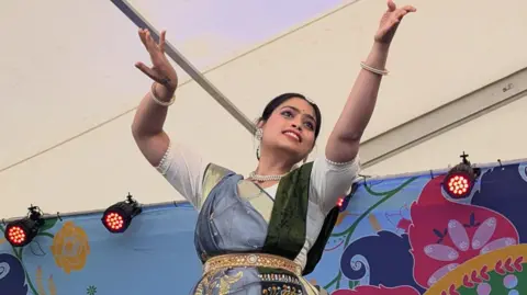 Art Asia A woman dances on stage in front of a colourful backdrop.