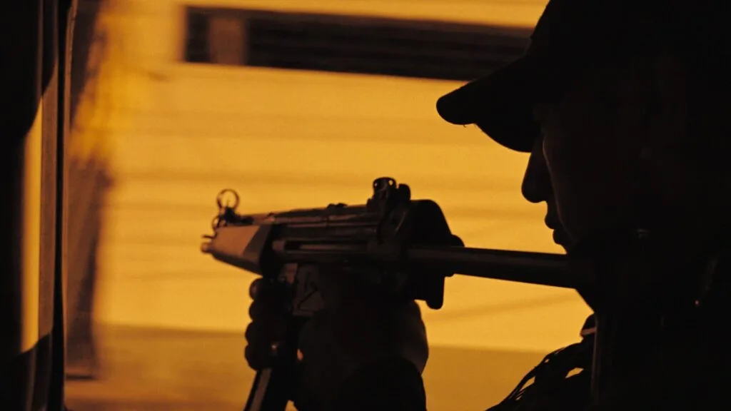 A man is seen in silhouette holding a gun.