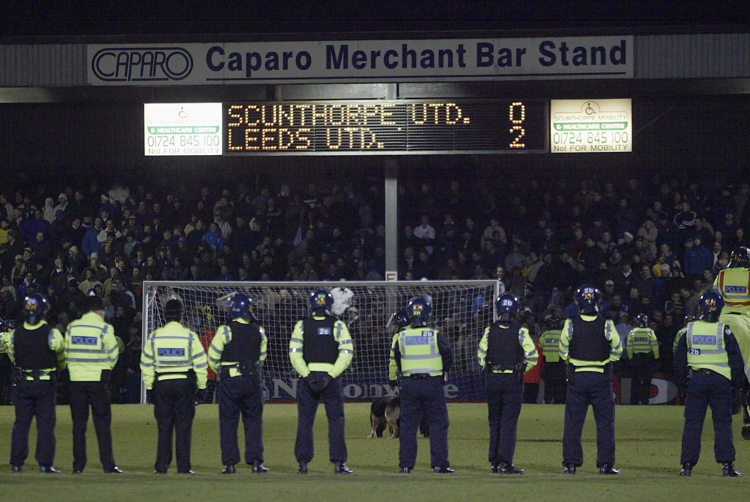 Police line up on a pitch as Scunthorpe are losing a match to Leeds United 2-0 in 2003