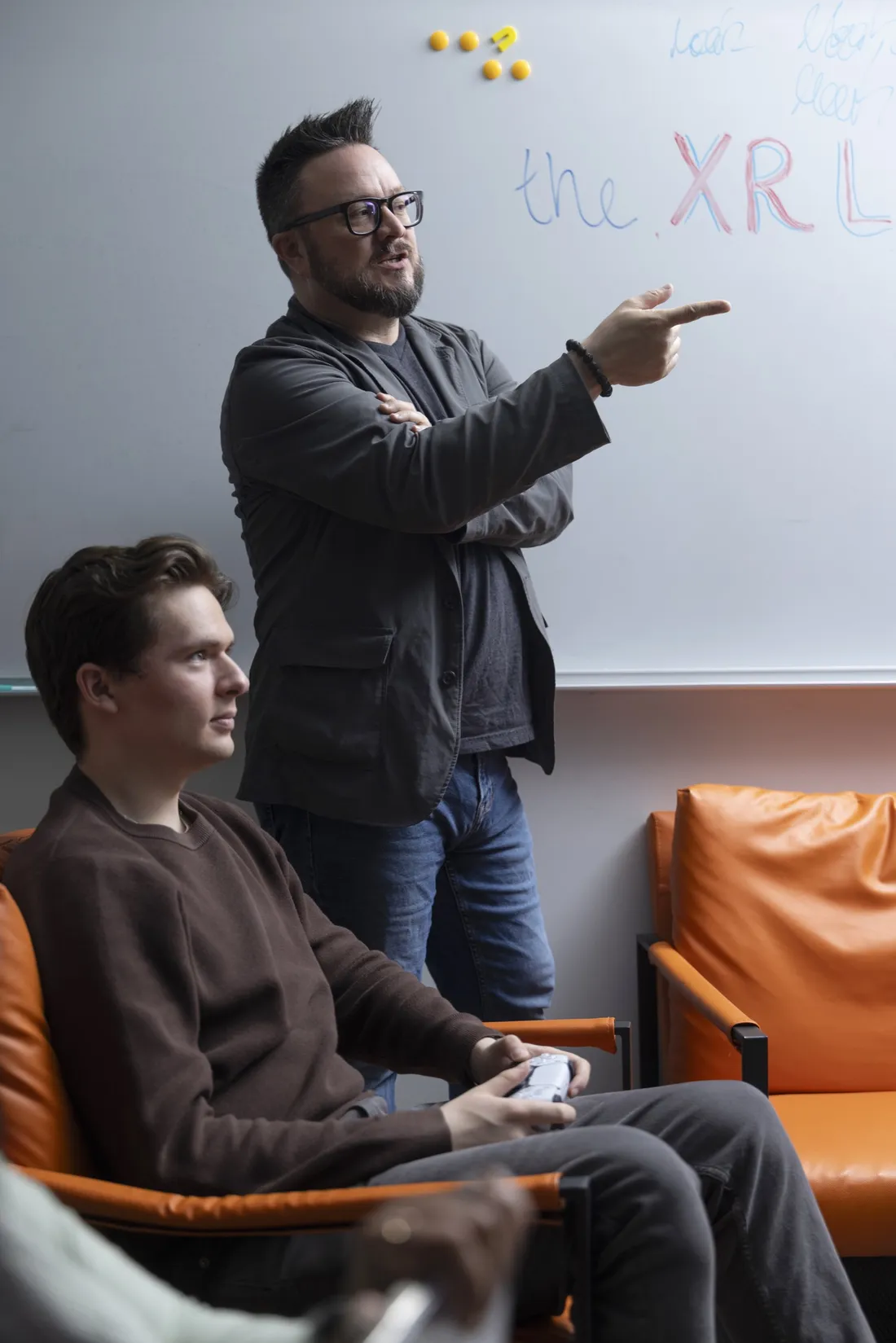 Professor Nick Bowman speaking with a student as he uses a video game system.