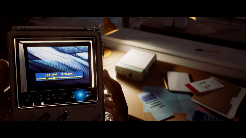 A hand holds a small gadget with a TV searching for a signal.