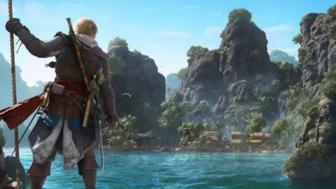 Ubisoft A scene in the new video game shows Edward standing on the bow of a ship, looking out at an island in the near distance. The sea water looks blue and vibrant to match the skies. The island is lush and green.