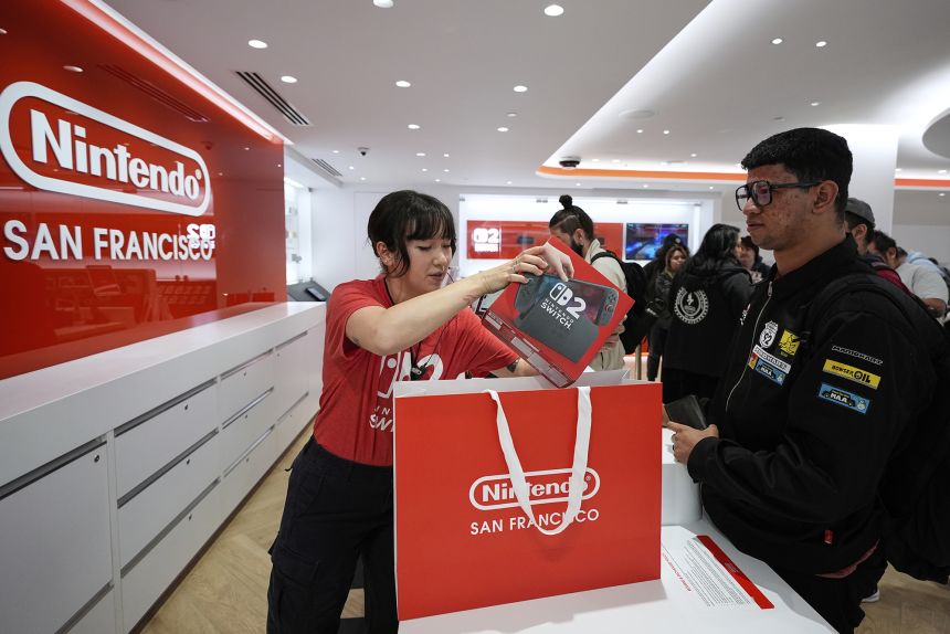Nintendo specialist ambassador Cyan Chang, left, places a new Nintendo Switch 2 video game console into a bag for Ronald Diaz in San Francisco on June 5, 2025.