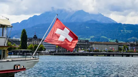 Getty Images A view of a Swiss flag on a boat on lake Lucerne and Lucerne city in central Switzerland