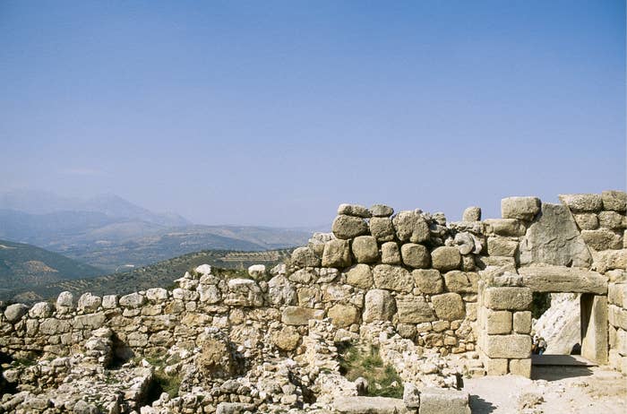 Ancient stone ruins with a doorway, set against a mountainous landscape under a clear sky
