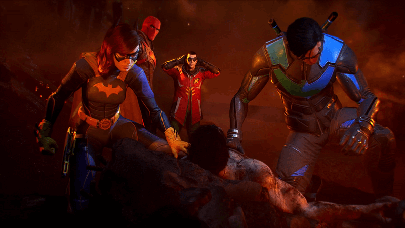 Image from Gotham Knights video game showing from left to right, Batgirl, Red Hood, Robin, and Nightwing mourning over the body of Batman amongst burning rubble.