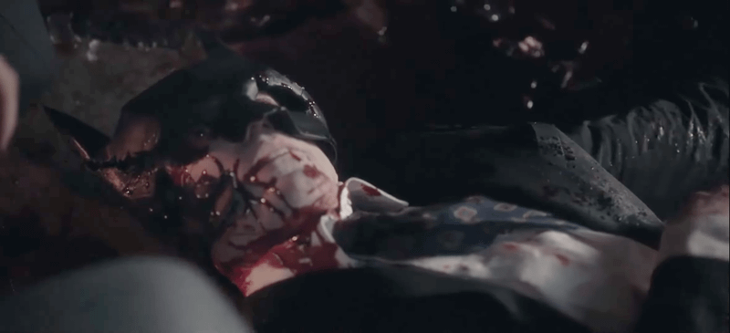 Image from CW's Gotham Knights showing Bruce Wayne bloody and dead on the pavement wearing his Batman mask and his eyes wide open.