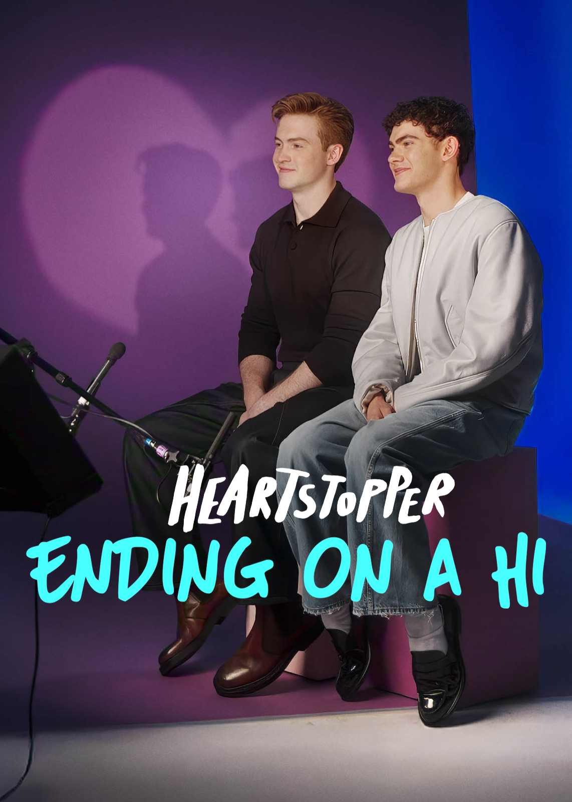 &Quot;Two Young Men Sit Side By Side On A Purple Bench In A Studio With Purple And Blue Lighting, Microphones In Front, Smiling, With Heartstopper: Ending On A Hi Text Overlayed.&Quot;