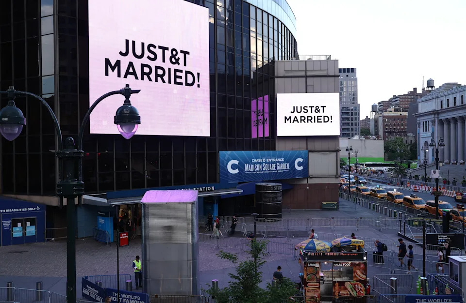 Giant screens showing the message "JUST&T MARRIED!" (T&T for Taylor and Travis) are seen outside Madison Square Garden, the reported venue for the wedding celebrations of pop singer Taylor Swift and pro-athlete Travis Kelce, in New York City on July 3, 2026. Swift and Kelce's official wedding plans are tightly under wraps, but New York is bracing to host the celebrity marriage of the year this week at Madison Square Garden. The wedding will reportedly take place Friday with a star-studded guest list of around 1,000, including models Gigi Hadid and Cara Delevingne, singer Selena Gomez, and actress Zoe Kravitz -- all known to be close Swift pals -- and Kelce's Kansas City Chiefs teammates. (Photo by CHARLY TRIBALLEAU / AFP via Getty Images)