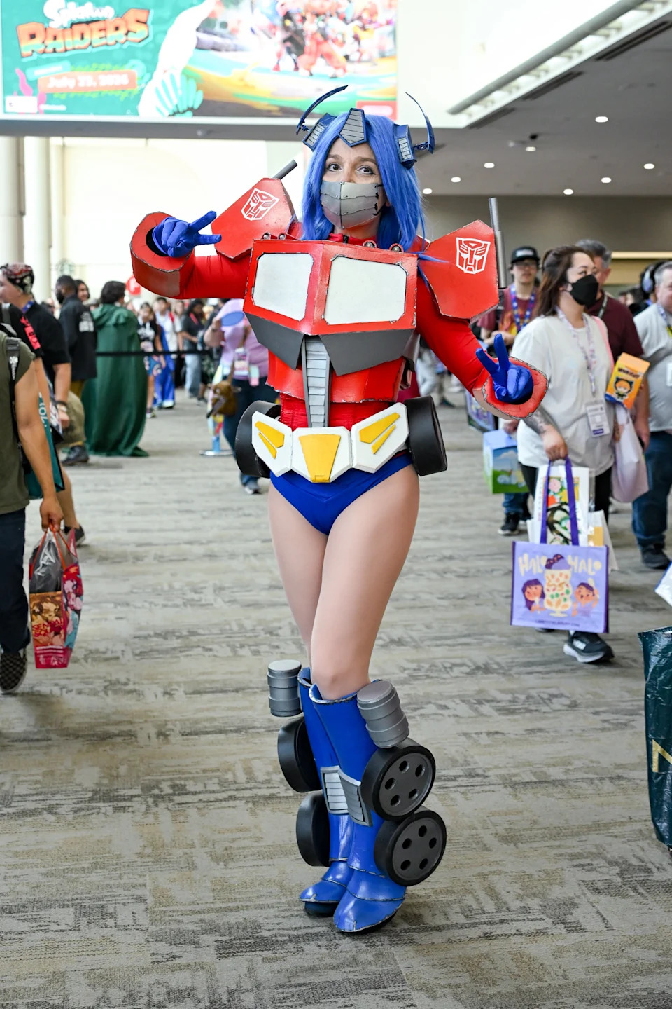 Person in a creative robot-inspired costume at a convention, posing with peace signs