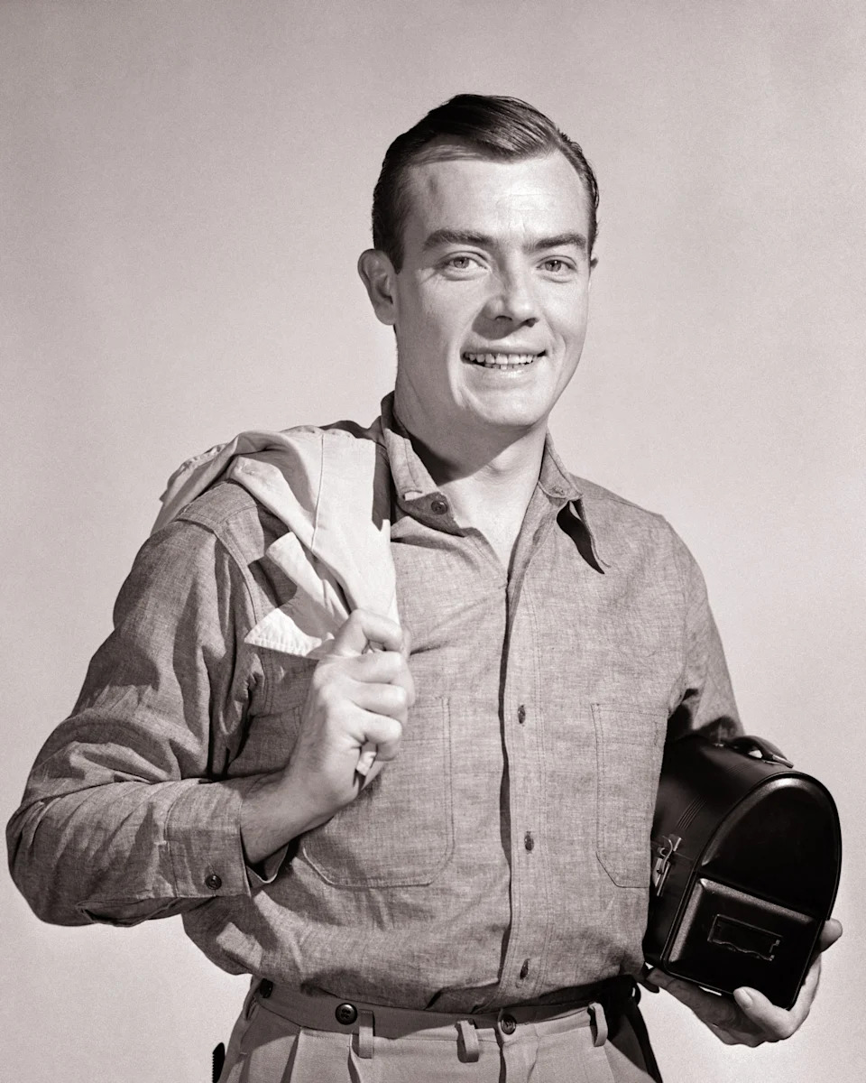 Person in vintage attire holding a small camera, smiling at the camera