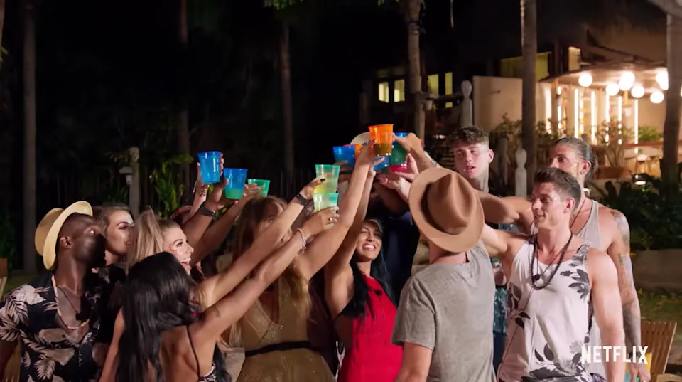 A group of people outdoors raising colorful cups in a celebratory toast