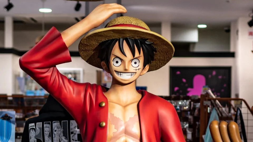 Statue of Monkey D. Luffy from "One Piece," wearing a straw hat and red jacket, in a store setting.
