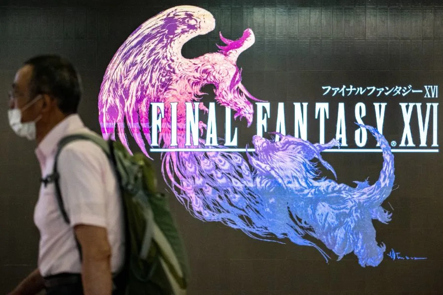 This picture taken on June 19, 2023 shows a man walking past an advertisement of Japanese gaming company Square Enix's "Final Fantasy XVI" video game, inside Shibuya station of Tokyo. (Photo by Philip FONG / AFP) (Photo by PHILIP FONG/AFP via Getty Images)