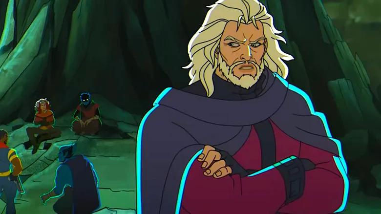 A man with long white hair and a beard stands with his arms folded wearing a blue cloak and a purple suit. There are superheroes sat in a cave behind him.