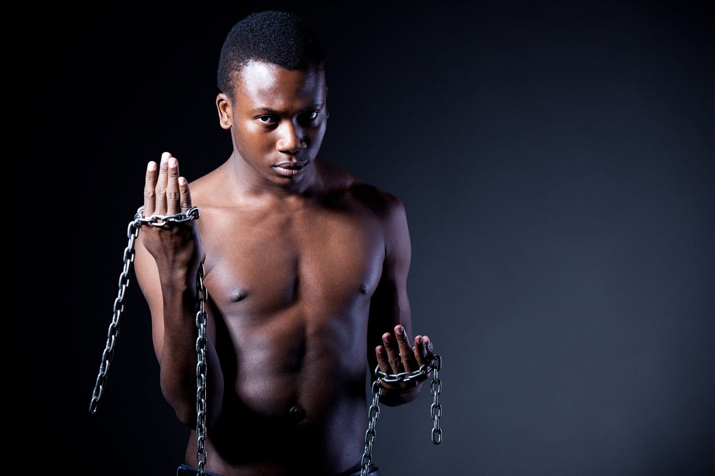 A Black man holding broken chains