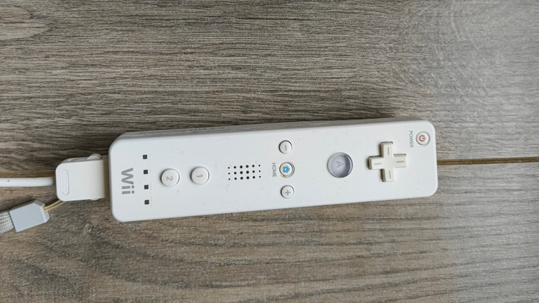 A Nintendo Wii controller with an offscreen Nunchuk attachment on a table