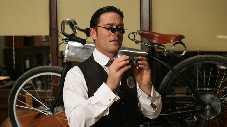 Yannick Bisson as Detective William Murdoch looking through glasses in Murdoch Mysteries.