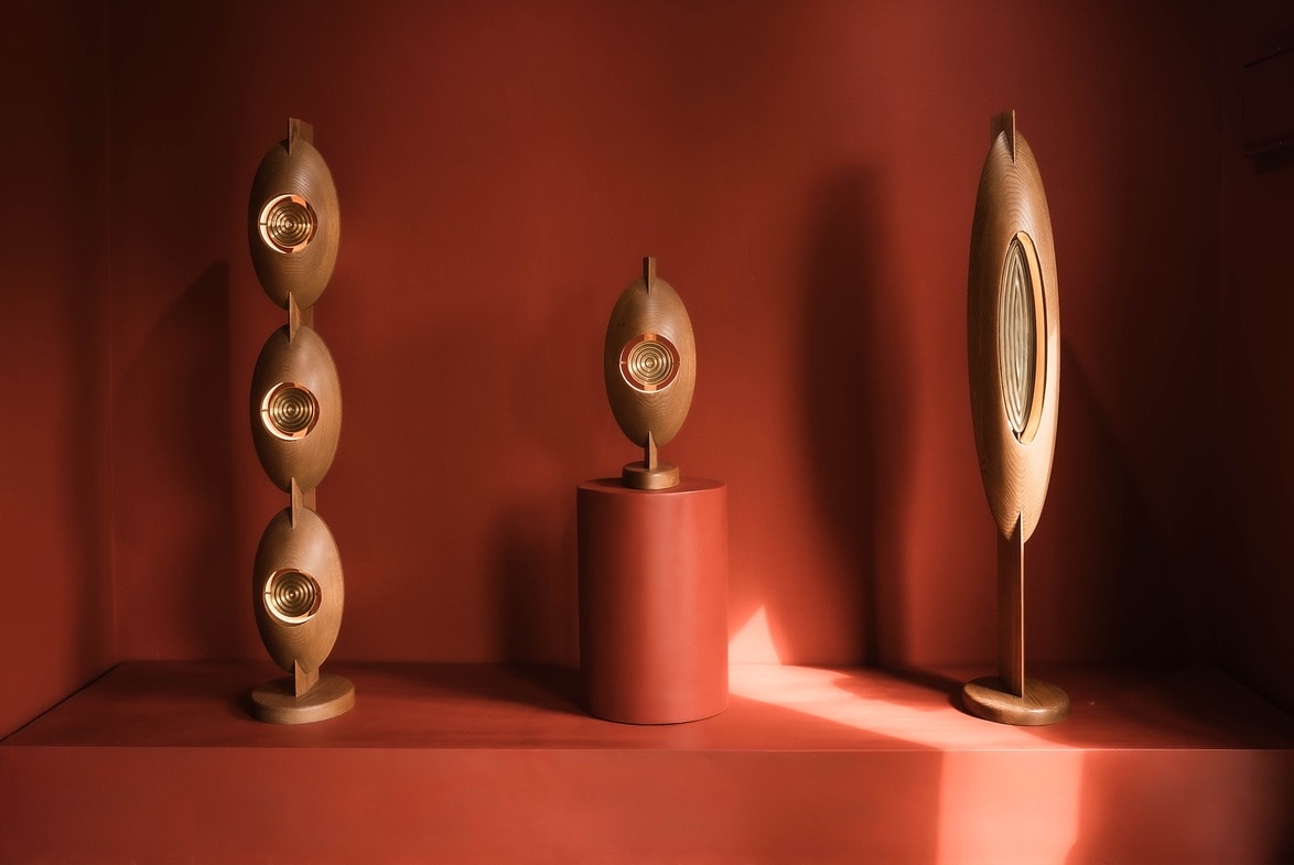 Three sculptural lamps in a minimalist room with a warm, reddish-brown color palette.