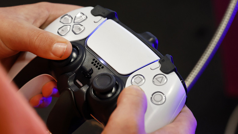 Hands holding a PlayStation 5 controller