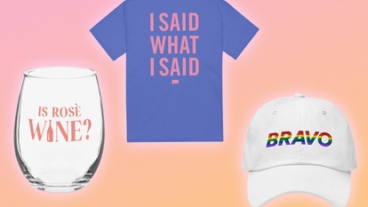 A stemless wine glass, A blue tee shirt, and a white bravo cap in front of a pink and orange backdrop.