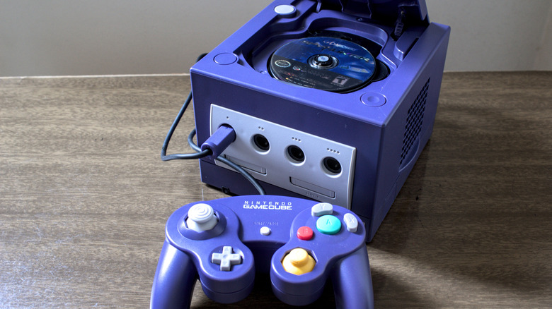 an opened Nintendo GameCube showing mini-disc tray and controller on a table