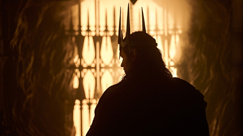 Charlie Vickers as Sauron wearing a crown and holding the One Ring in The Lord of the Rings: The Rings of Power