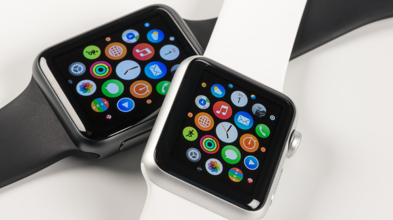 A white-banded Apple Watch lying on top of a black-banded Apple Watch Ultra.