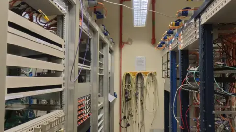 The Elstree Project Racks of computer equipment with wires.