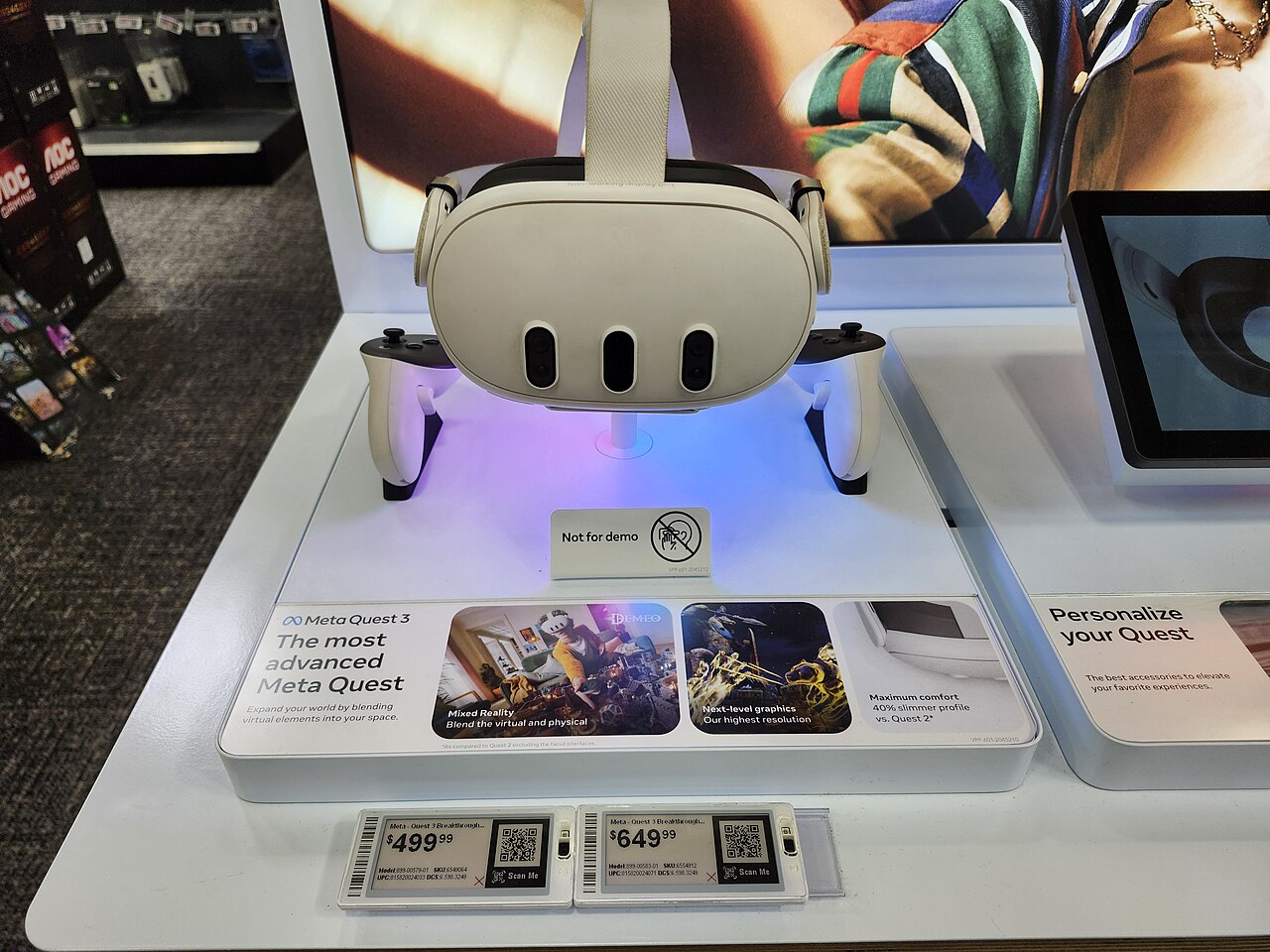 A Meta Quest 3 headset and Touch Plus controllers on a retail display stand with price tags reading 499 and 649 dollars