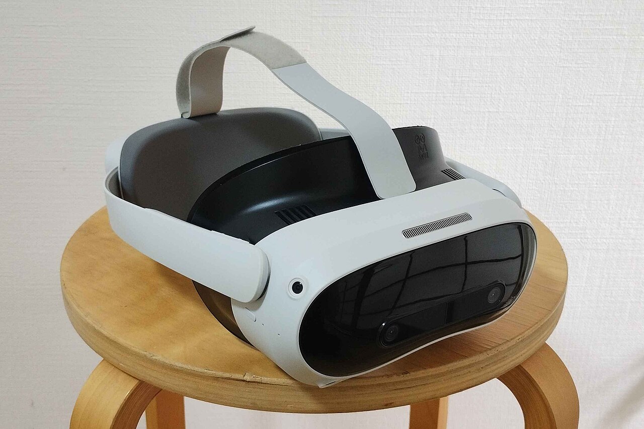 Pico 4 Ultra standalone VR headset resting on a wooden stool, front lens housing and white strap visible
