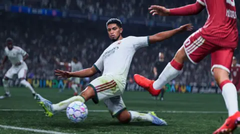 Electronic Arts A screenshot from EA's EA FC 27, showing England's Jude Bellingham in white on the football pitch, saving a pass from the opposing team in red.
