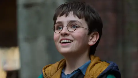 Aidan Monaghan/HBO Dominic McLaughlin in round glasses in a scene from Harry Potter