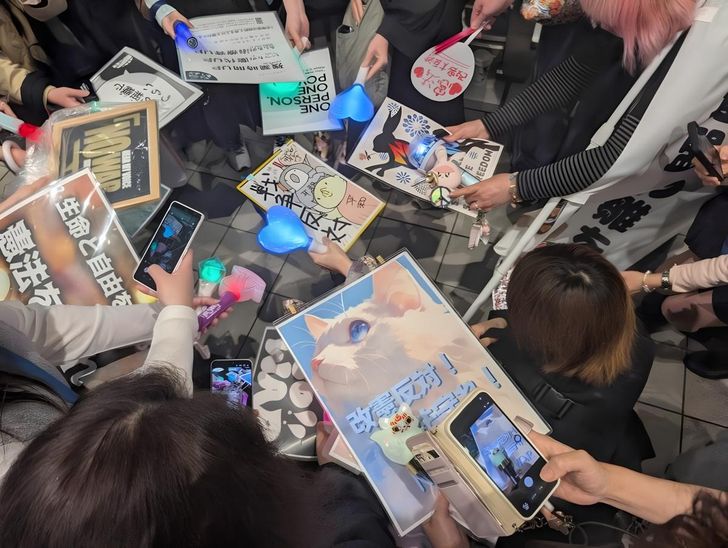 Demonstrators gather their K-pop lightsticks to take a picture during the  'No War' street rally in Osaka, Japan. Captured from X