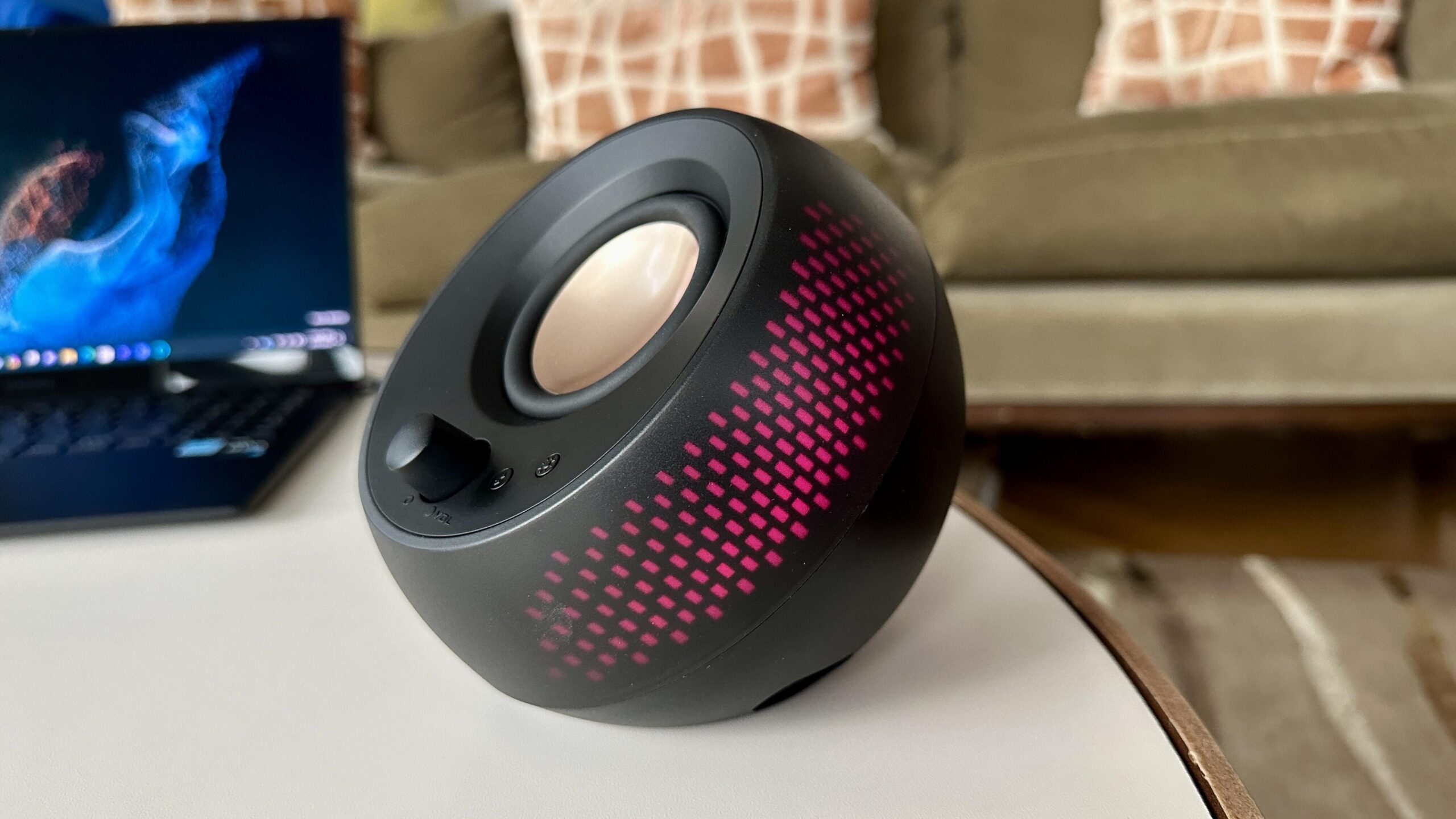 The black Creative Labs Pebble X with RGB lighting lit up red on a coffee table.