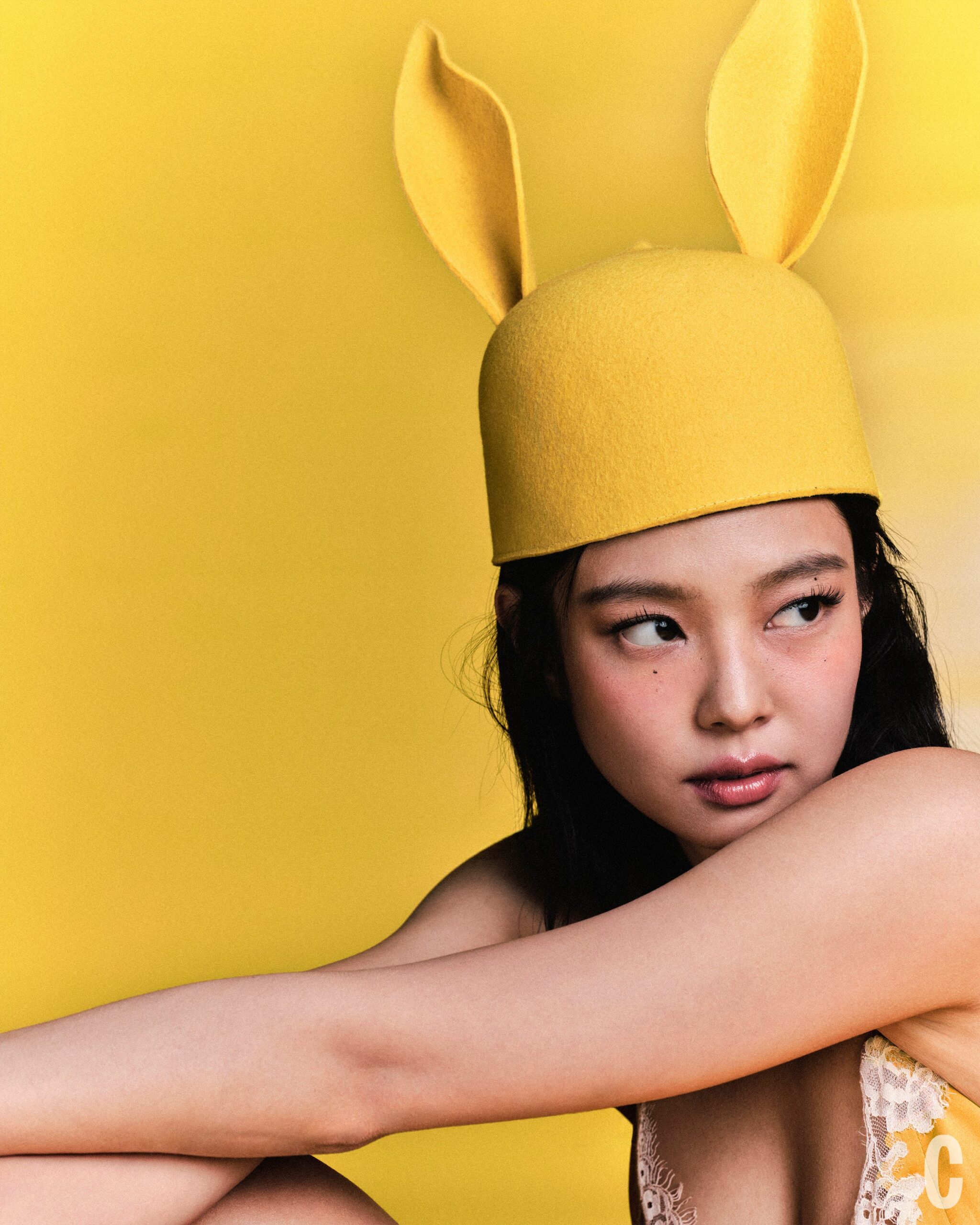Young woman with a yellow bunny hat poses against a bright yellow background.