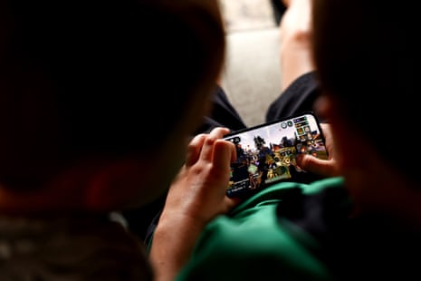 Young children hold an iPhone while using Roblox