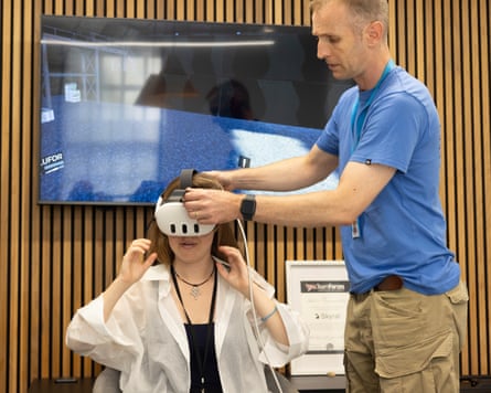 a man helps to fit a VR headset on a sitting woman